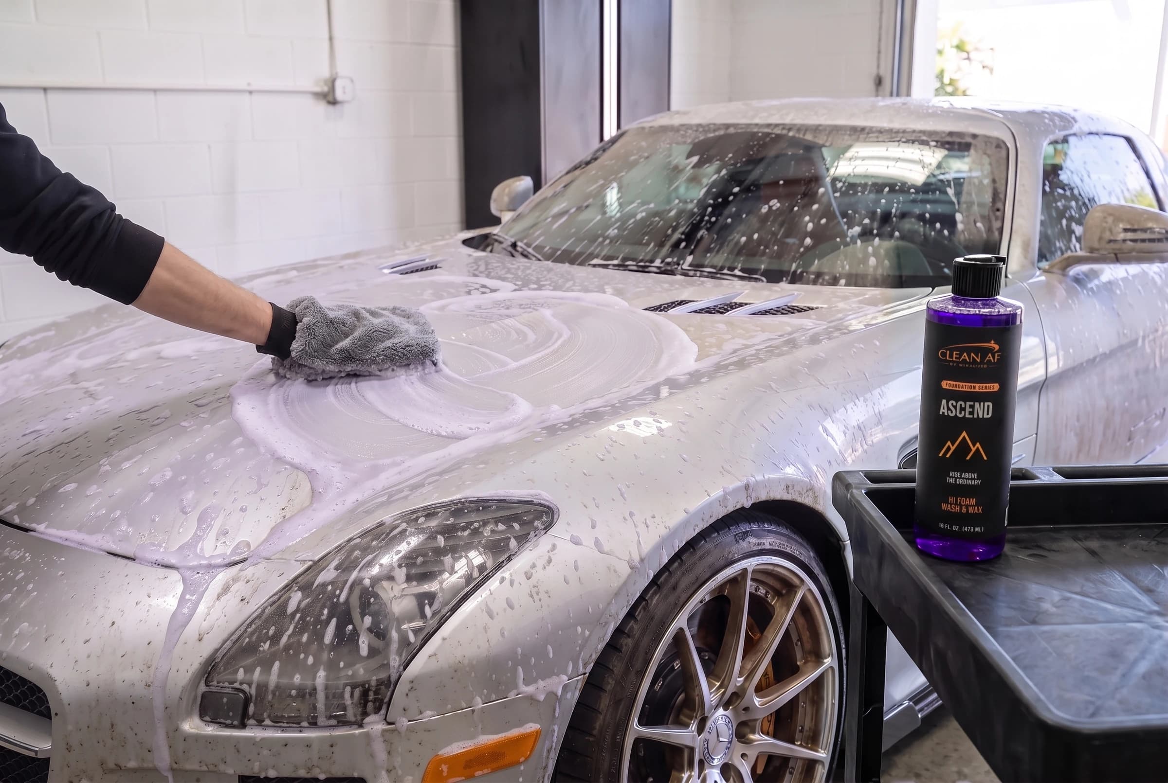 A wash mitt scrubbing the wet, foamed silver SLS
