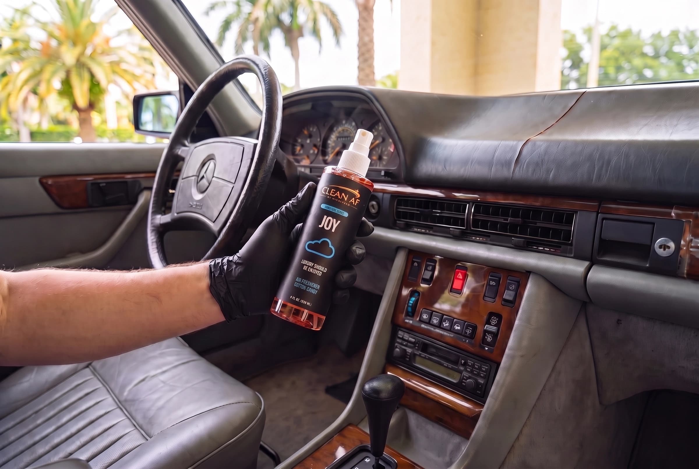 JOY held beside the air-conditioning controls in the gray Mercedes cabin
