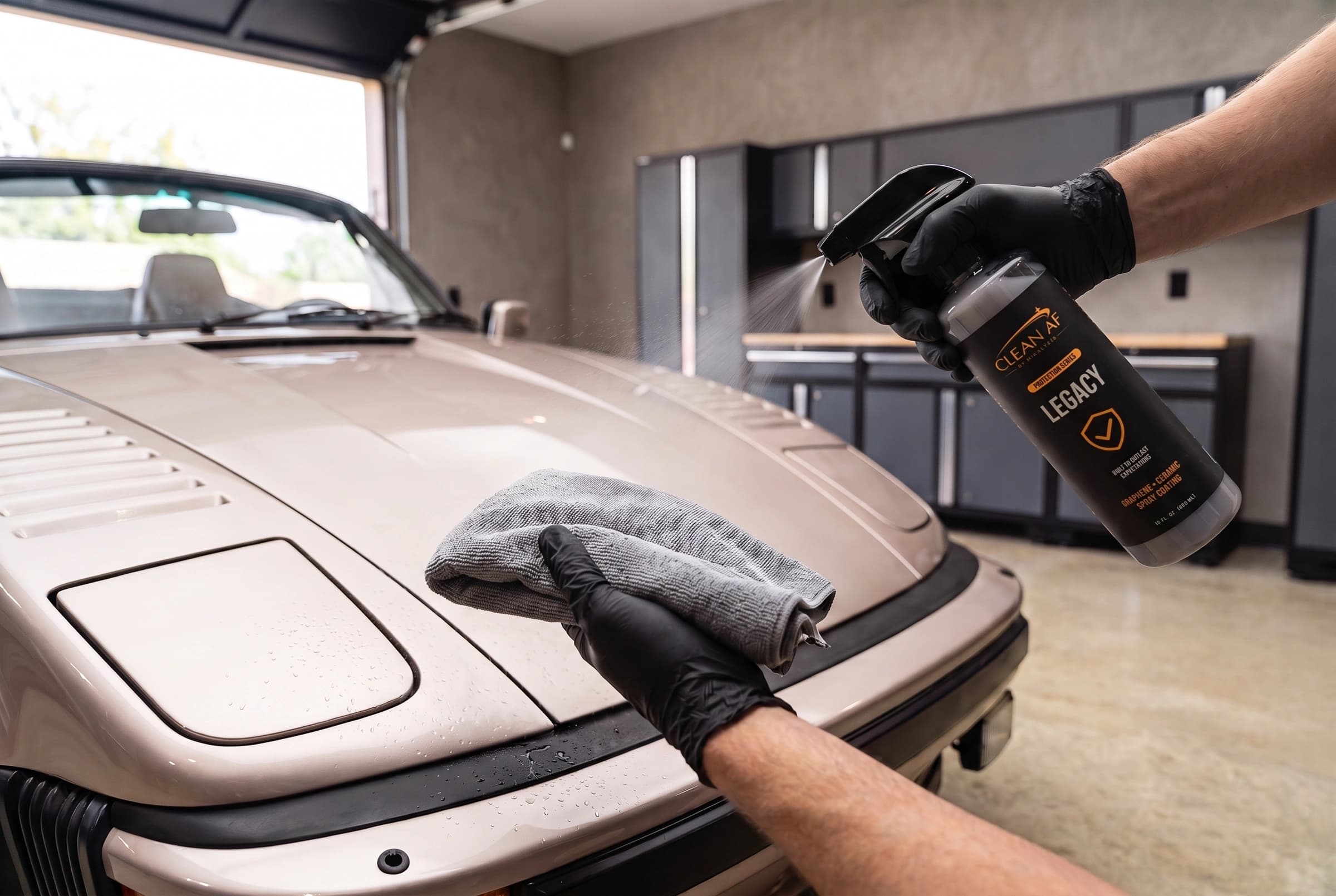 LEGACY spraying toward a microfiber towel held above the pale metallic Porsche paint