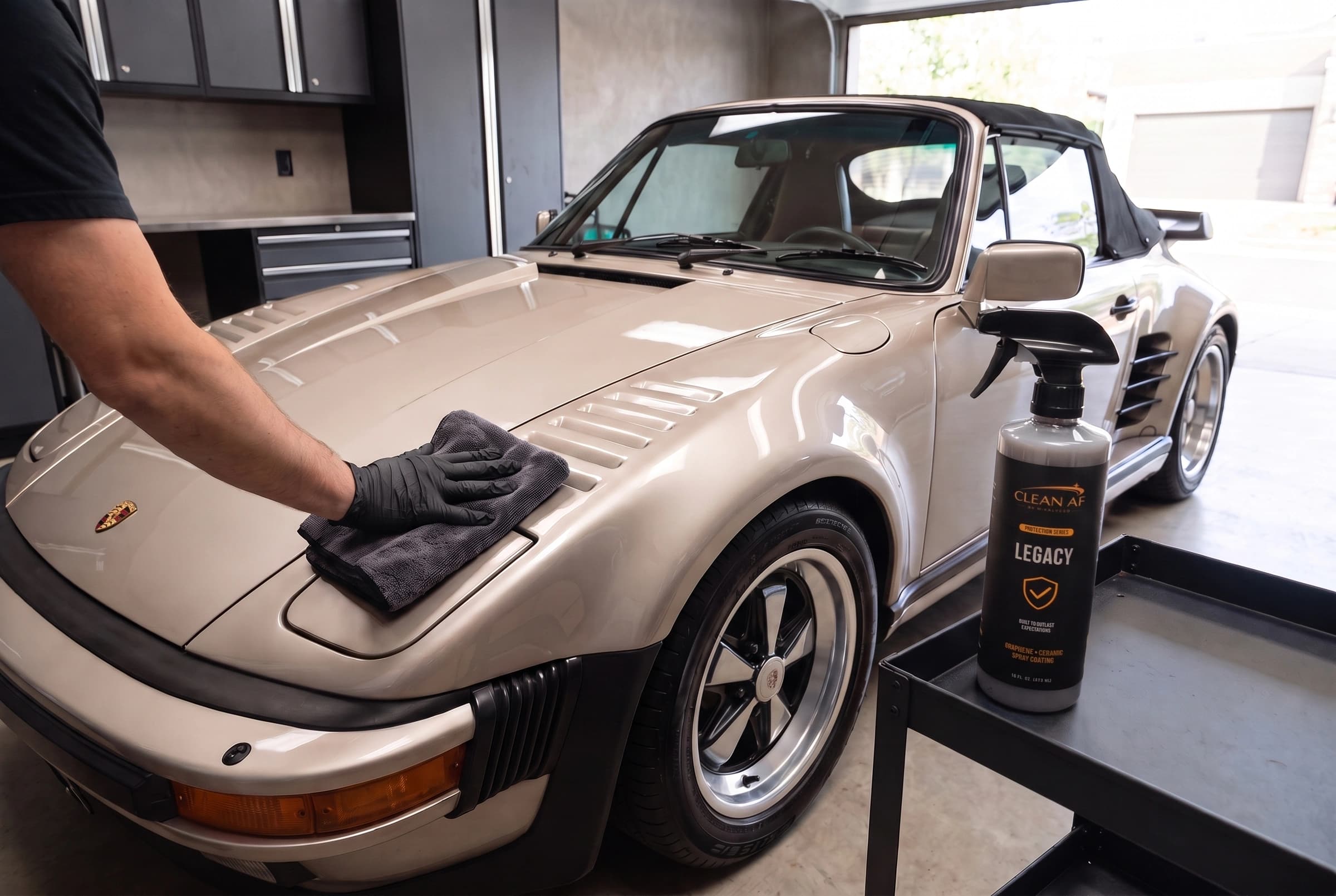 A gloved hand buffing the pale metallic Porsche with a folded microfiber towel beside LEGACY